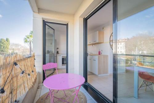 une table et des chaises roses dans une chambre avec cuisine dans l'établissement Le St Charles, Charmant T2, Terrasse, Centre ville, à Montpellier