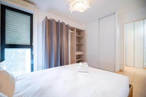 une chambre avec un lit blanc et une grande fenêtre dans l'établissement Le St Charles, Charmant T2, Terrasse, Centre ville, à Montpellier