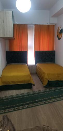 twee bedden in een kamer met oranje gordijnen bij J & A in Tirana