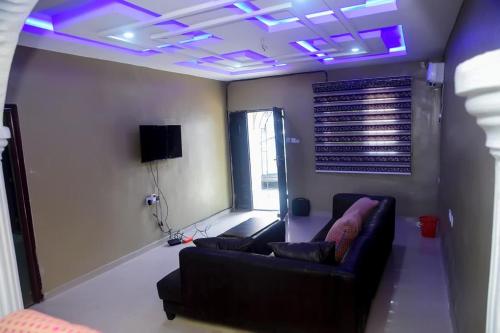 a living room with a couch and purple lights at Mena's Home & Apartment in Ughelli