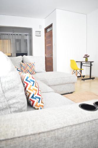 Juliett Wonder Furnished Apartment في نيروبي: أريكة بيضاء مع وسائد عليها في غرفة المعيشة