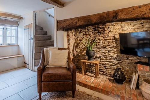 sala de estar con silla y pared de piedra en The Gamekeeper's Cottage - Stunning 2 Bed! en Leafield