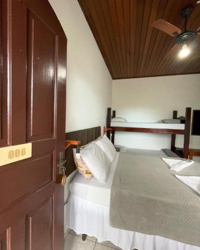 1 dormitorio con 1 cama y puerta de madera en CHILL INN HOSTEL & POUSADA CENTRO en Paraty