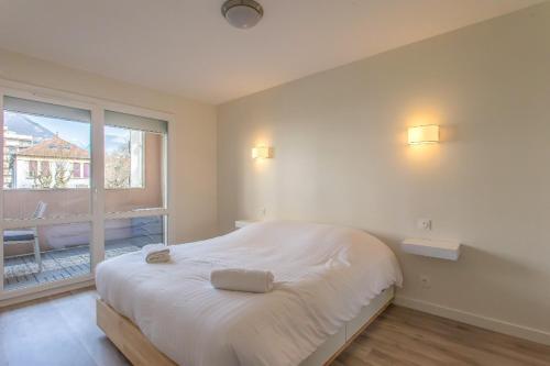 ein Schlafzimmer mit einem Bett und einem großen Fenster in der Unterkunft Le Petit Parfait in Grenoble