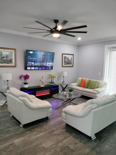 a living room with white couches and a flat screen tv at Villa White Rock in Tampa in Tampa
