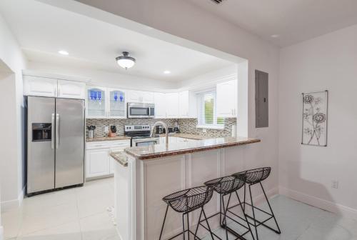 uma cozinha com um frigorífico e 2 bancos de bar em Discover Serenity in this Tranquil Miami Home em Miami