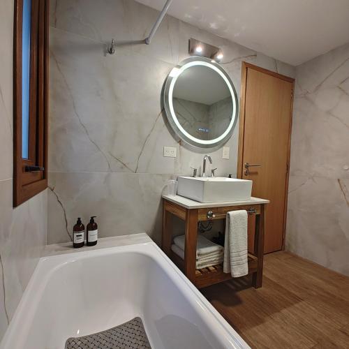 y baño con bañera, lavabo y espejo. en ANFITEATRO APARTS & LOFTS en San Carlos de Bariloche