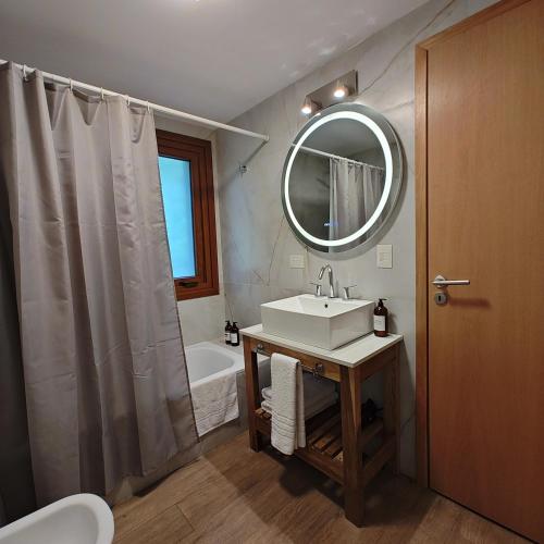 a bathroom with a sink and a mirror and a tub at ANFITEATRO APARTS & LOFTS in San Carlos de Bariloche