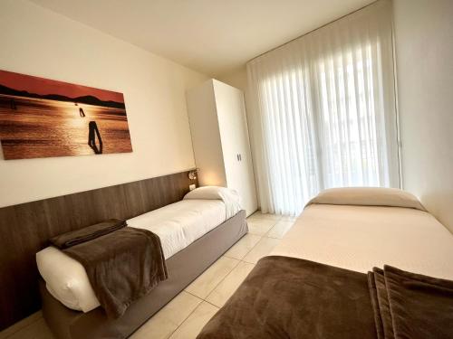 um quarto com 2 camas e uma grande janela em Residenza Roma Marina em Sottomarina