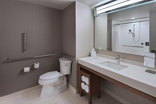 a bathroom with a toilet and a sink and a mirror at Courtyard by Marriott Jackson Madison in Madison