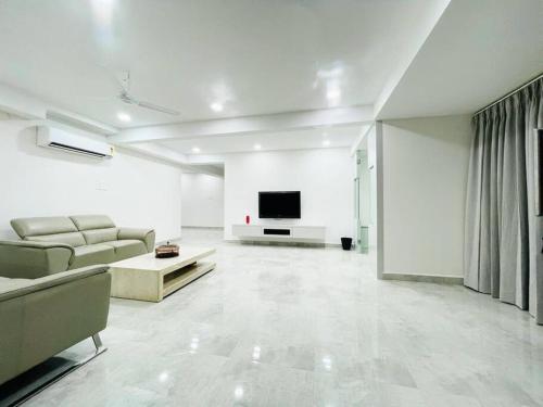 a white living room with a couch and a tv at Dream Pent House in Hyderabad