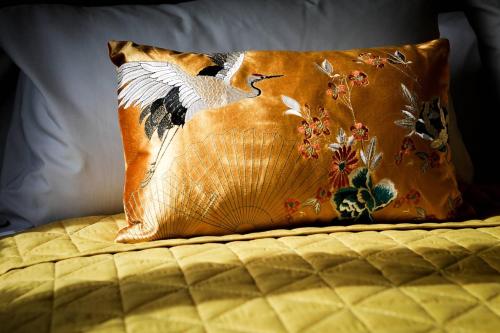 a pillow with a bird on it sitting on a bed at Little Bright House in Whitstable