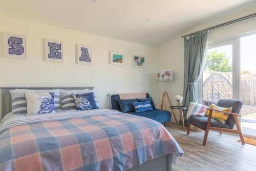 a bedroom with a bed and a chair and a window at Pear Tree Cabin in Whitstable