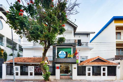 a white building with a tree in front of it at Mayhouse Vũng Tàu Hotel TPVT in Vung Tau