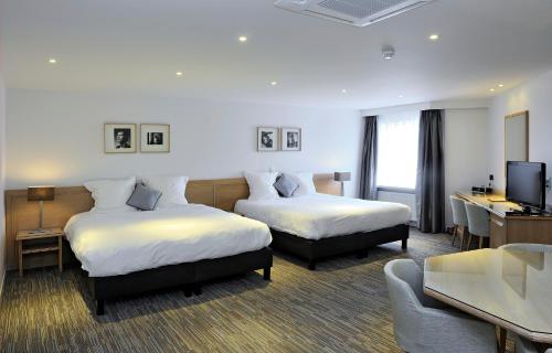 a hotel room with two beds and a television at Parkhotel Kortrijk in Kortrijk