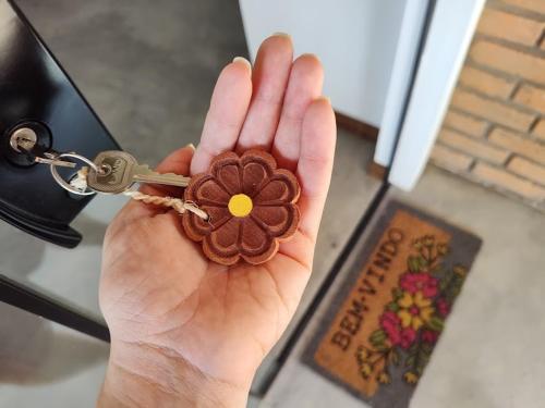 韦尔卡鲍Flor e Luz Chalés的手持钥匙链的人,手持花