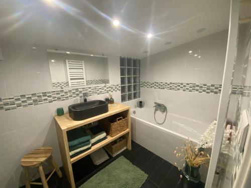 a bathroom with a sink and a tub and a mirror at Chambre Sayulita/Spa/piscine in Idron