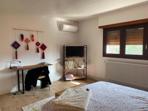 Cette chambre comprend un bureau, une table et une télévision. dans l'établissement Chambre Sayulita/Spa/piscine, à Idron