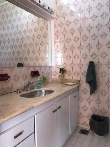 a bathroom with a sink and a pink tiled wall at Alojamiento por día/mes/año femenino Mafalda Viedma in Viedma