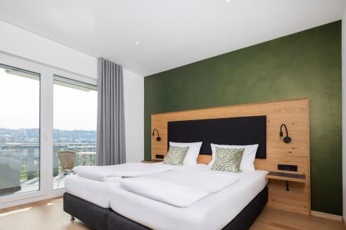 a bedroom with a large bed with a green wall at Hotel Restaurant Sennerbad in Ravensburg