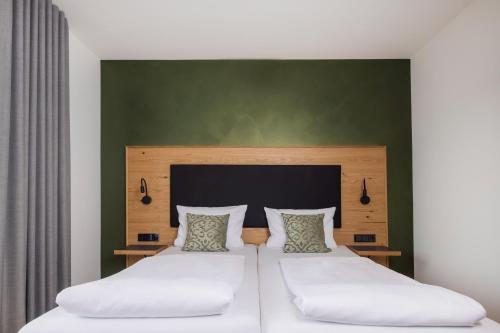 a bedroom with two beds and a green wall at Hotel Restaurant Sennerbad in Ravensburg