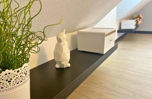 a white rabbit figurine sitting on a black table next to a plant at [Rêve doré] Studio Équipé, Wifi, Unique in Lourdes