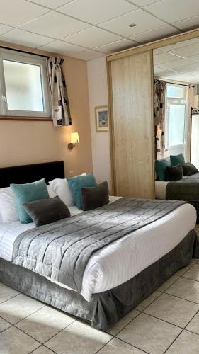 a bedroom with a large bed with blue pillows at La Maison Blanche in Sangatte