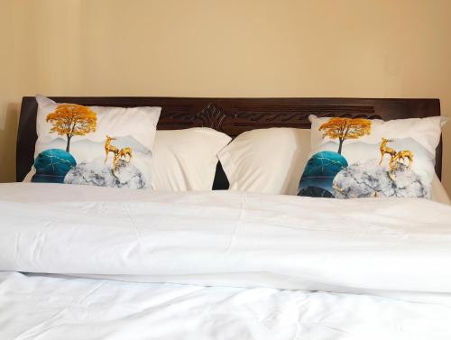a bed with white sheets and pillows with deer on them at The Chocolate House in Athi River