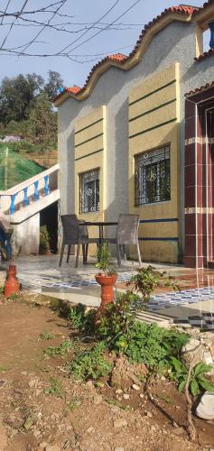 a house with two chairs and a bench in front of it at دار الضيافة تازكة Maison d'hôtes Tazekka in Taza