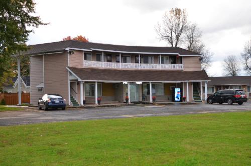 a building with two cars parked in a parking lot at Aquarius Motel in Perth