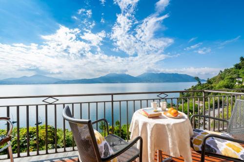 a table and chairs on a balcony with a view of the water at Hotel La Rondinella in Cannero Riviera