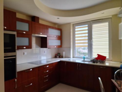 a kitchen with wooden cabinets and a sink and a window at Apartament Sweet Stalowa Wola in Stalowa Wola