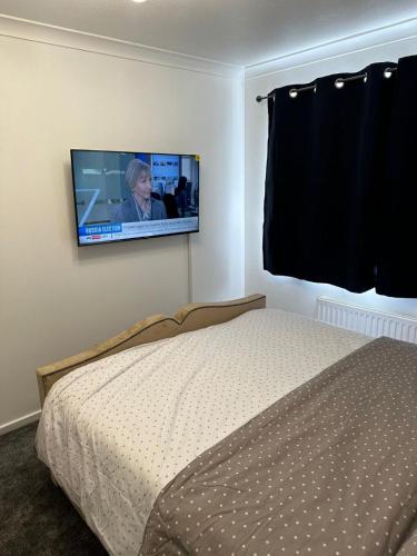 a bedroom with a bed and a flat screen tv on the wall at Lovely Two Bedroom Flat in Thamesmead