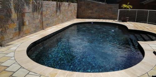 a swimming pool in a backyard with a brick wall at Lodge Garden in Saint-Pierre