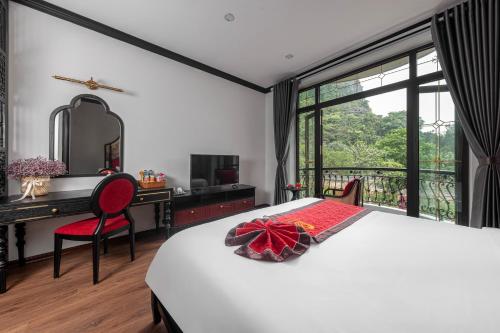 a bedroom with a bed and a desk and a window at Indochine Boutique Hotel Ninh Bình in Ninh Binh