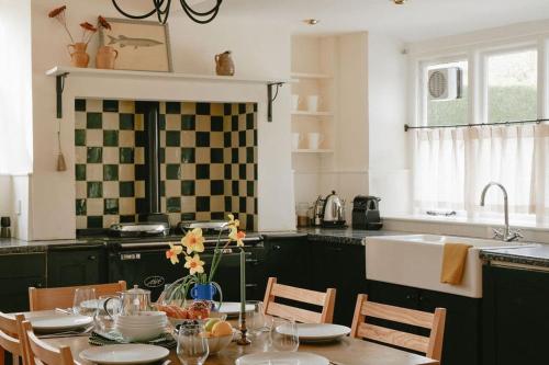 a kitchen with a table with chairs and a sink at Trinity Farmhouse - Stunning House & Gardens! in North Cerney