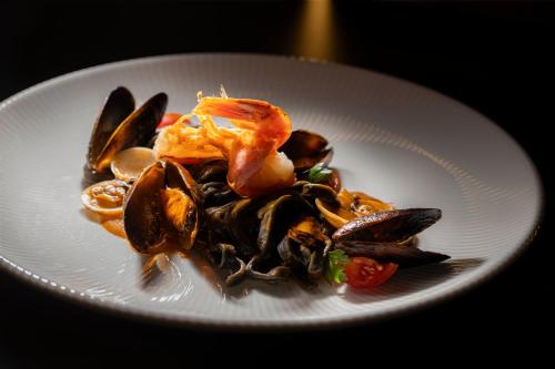 a white plate of food with mussels and shrimp at Grand Hotel Zagreb in Zagreb