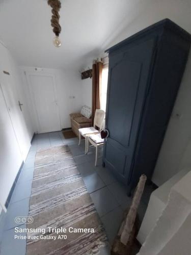 a living room with a blue door and a chair at Maison de charme à Annebault avec jardin clôt et barbecueA in Annebault