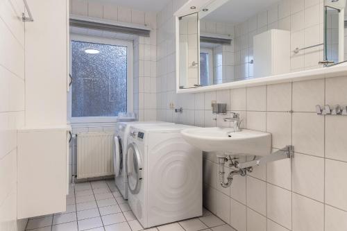 a white bathroom with a washing machine and a sink at 50180... in Harlesiel