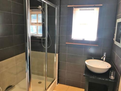 a bathroom with a glass shower and a sink at Aule Apartment in Bembridge