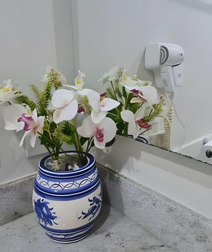 a blue and white vase with flowers in front of a mirror at Studios Exclusivos Xavishome Granja Brasil Itaipava in Itaipava