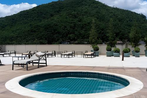 a swimming pool with tables and chairs and a mountain at Studios Exclusivos Xavishome Granja Brasil Itaipava in Itaipava
