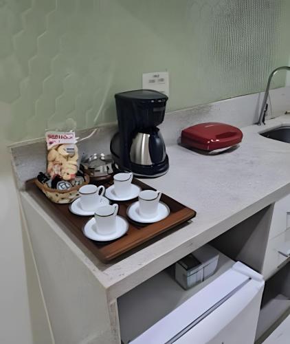 a tray with cups and saucers on a kitchen counter at Studios Exclusivos Xavishome Granja Brasil Itaipava in Itaipava
