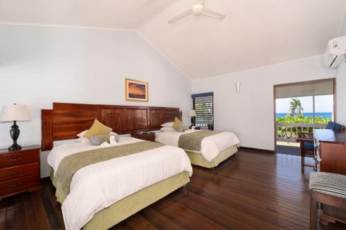 a hotel room with two beds and a balcony at Villa Turrasann in Runaway Bay