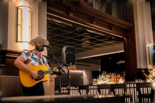 a man playing a guitar in front of a microphone at The Union Station Nashville Yards, Autograph Collection in Nashville