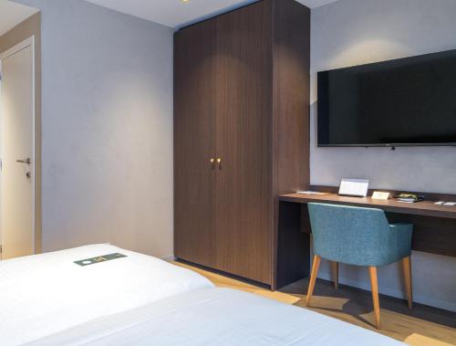 a hotel room with a bed and a desk with a television at Business By Parkhotel -ANNEX- in Kortrijk