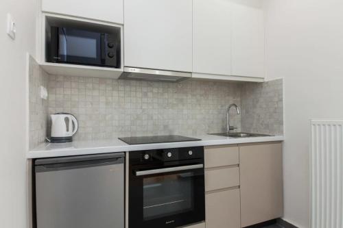 a kitchen with a microwave and a stove and a sink at Stylish New Paradise Apt for 2 in Marousi in Athens