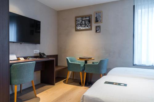 ein Hotelzimmer mit einem Bett, einem Schreibtisch und Stühlen in der Unterkunft Business By Parkhotel -ANNEX- in Kortrijk