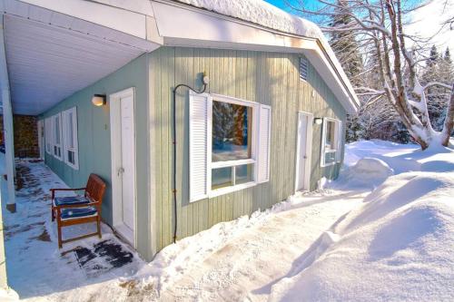 サン・ドナ・ド・モントカームにあるLa Tanière - Retraite en nature avec foyer au boisの雪の中の椅子と窓のある家