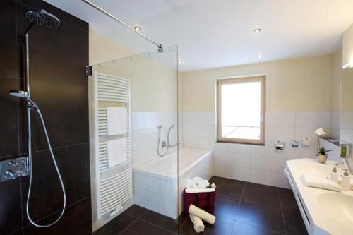 ein Badezimmer mit einer Dusche, einer Badewanne und einem Waschbecken in der Unterkunft Naturparkhotel Adler in Wolfach